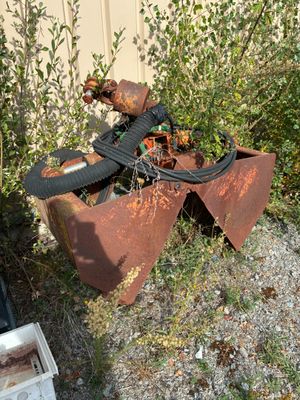 un objet métallique rouillé posé dans l'herbe à côté d'une poubelle