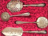 five silver spoons in a box on a red cloth