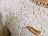 a woman wearing a white sweater with a gold broocher on it