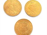 trois pièces d'or de tailles et de formes différentes posées sur une surface blanche