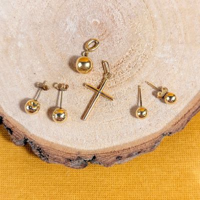 three pairs of gold cross stud earrings on a piece of wood