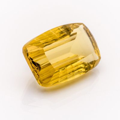 a close up of a yellow sapphire stone on a white surface