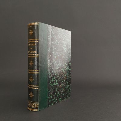 an old book with a green cover and gold trim