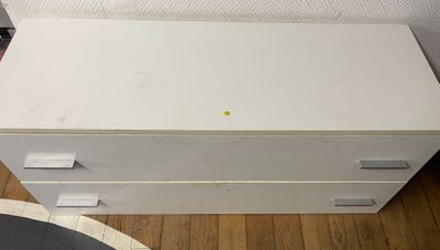une commode blanche posée sur un parquet, dans une pièce