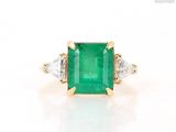 an emerald and diamond three stone ring in yellow gold