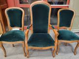 trois chaises recouvertes de velours vert, placées devant une porte
