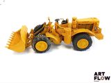 un petit bulldozer jaune posé sur une surface blanche