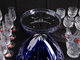 many glasses and a vase on a table with a black background