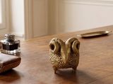a small animal figurine sitting on a table next to a pen and inkwell