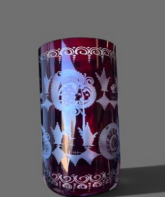 un vase rouge orné de motifs blancs sur un fond gris