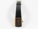 gros plan d'une montre sur une surface blanche avec un bracelet noir