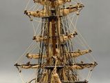 wooden model of a tall sailing ship on a white surface