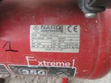 a close up of a red air compressor on the ground