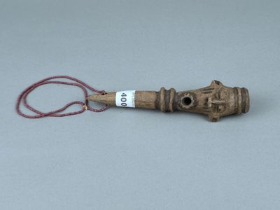 un petit objet en bois auquel est attaché un cordon rouge