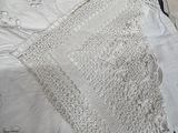 a white crocheted blanket on a bed next to a pillow