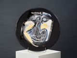 painting on a black plate on a white pedestal with a black background