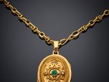 a gold necklace with a green stone in the center