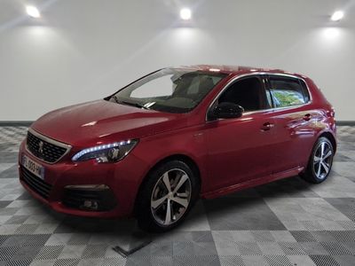 une voiture rouge est garée dans une pièce au sol en damier