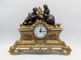 une horloge en or sur laquelle sont représentés un garçon et une fille
