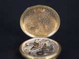 a gold pocket watch sitting on a black surface