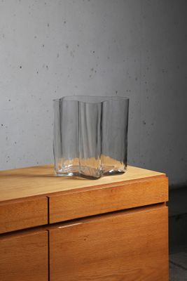 a glass on top of a wooden dresser next to a wall