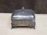 silver plated box with a bird on top sitting on a wooden table
