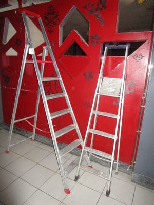 deux échelles posées devant un mur rouge