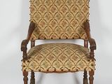 une vieille chaise avec un dossier rembourré à motifs et des pieds en bois