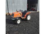 un petit tracteur orange garé devant un immeuble