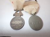 two medals on a white table with a ribbon around them