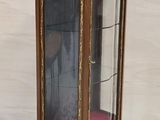 une vitrine en verre avec un coussin rouge posé par terre