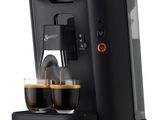 une machine à café noire avec deux tasses de café devant elle