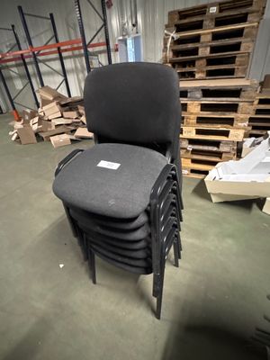 une pile de chaises dans un entrepôt, avec des palettes en arrière-plan