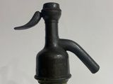 an old green glass bottle with a black handle sitting on a table