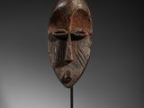 un masque en bois posé sur un socle
