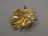 an image of a gold plated brooch on a gray surface