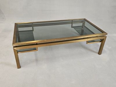 une table basse en laiton avec un plateau en verre, sur fond blanc