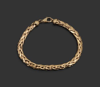 un bracelet en or avec un motif tressé sur fond noir