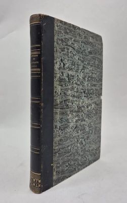 an old book with a black cover sitting on top of a white surface