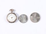 a small silver pocket watch next to a quarter