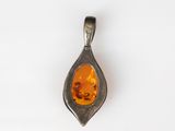 a silver pendant with an orange stone inside of it