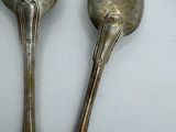 two silver spoons sitting next to each other on a table