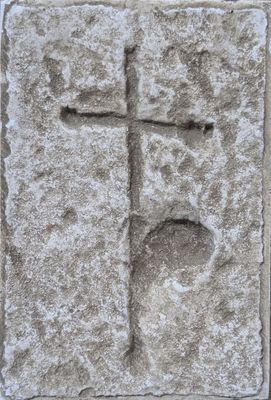 a cross carved into a stone block on the side of a building