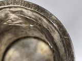 a close up view of a silver vase with writing on it