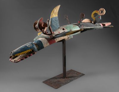 une sculpture d'oiseau en bois posée sur un socle en métal