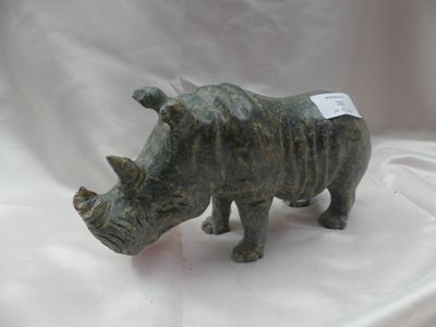 une statue représentant un rhinocéros debout sur un tissu blanc