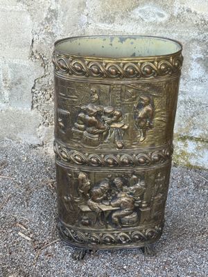 a metal trash can sitting on the ground in front of a wall