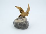 statue of a bird perched on a rock on a white background
