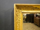 gold framed mirror in a dark room with a wooden floor