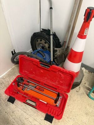 une boîte à outils rouge contenant des outils, posée à côté d'un cône de signalisation